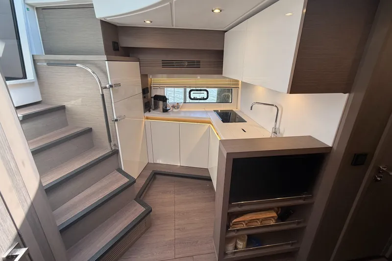 Slide: The Image of Modern kitchen interior of 2023 Beneteau Gran Turismo 45 yacht, featuring sleek cabinetry and compact design. - 15