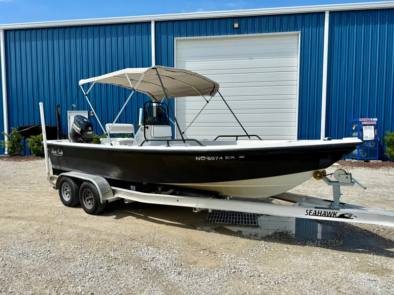 Slide: The Image of 2015 Stott Craft SCV 2160 Bay boat on trailer, parked outside blue warehouse. - 2