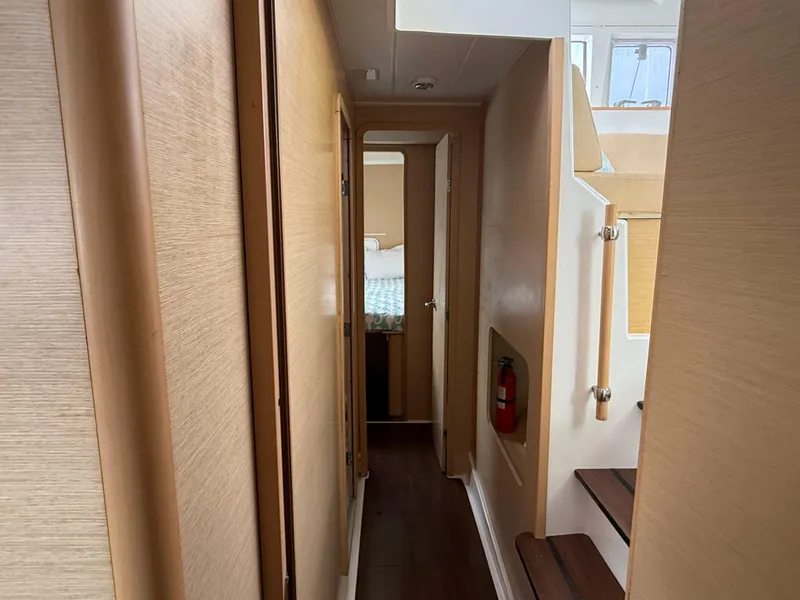 Slide: The Image of Narrow hallway inside 2010 Lagoon 400 Owner's Version yacht, featuring wooden paneling and stairs. - 22