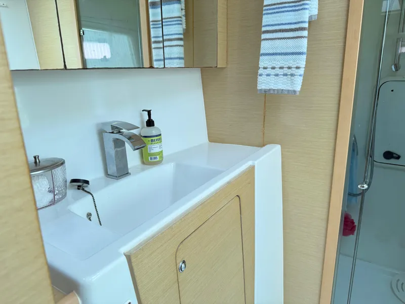 Slide: The Image of Bathroom sink area in 2010 Lagoon 400 Owner's Version yacht, featuring modern fixtures and cabinetry. - 29