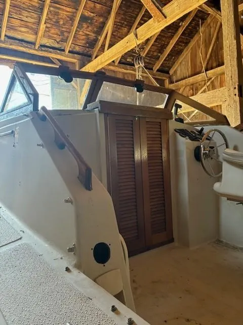 Slide: The Image of 1990 Custom North End Composites Point boat interior with wooden doors and steering wheel in a rustic shed. - 3