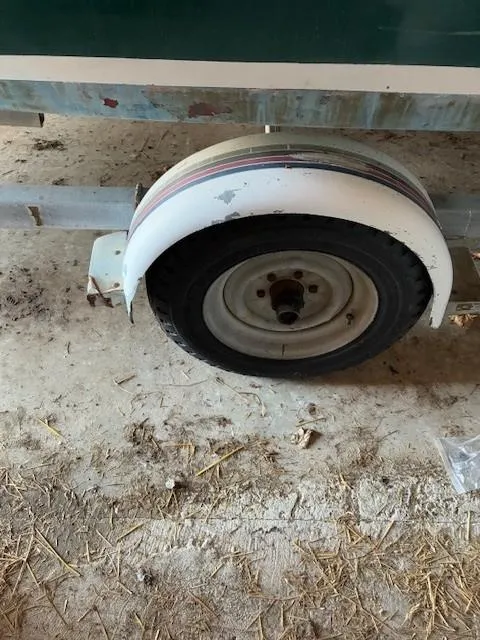 Slide: The Image of Trailer wheel of a 1990 Custom North End Composites Point boat on a sandy surface. - 9