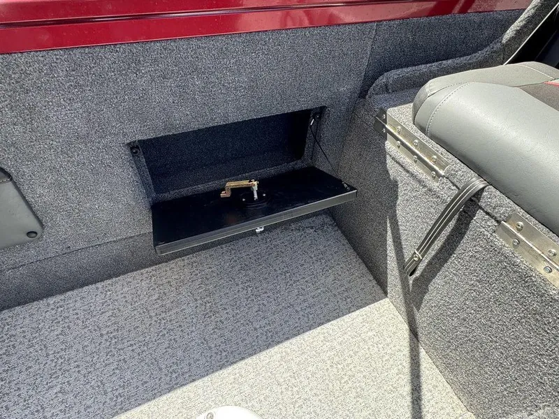 Slide: The Image of 2024 Tracker Targa™ V-18 Combo interior storage compartment with open lid and gray upholstery. - 37