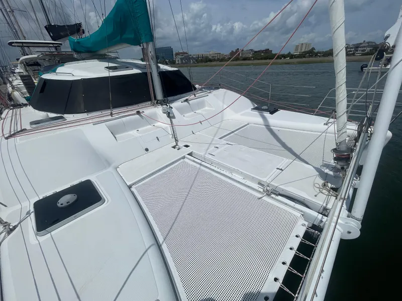 Slide: The Image of Seawind 1000 catamaran deck, 2001 model, with netting and sails, docked by the shore. - 11
