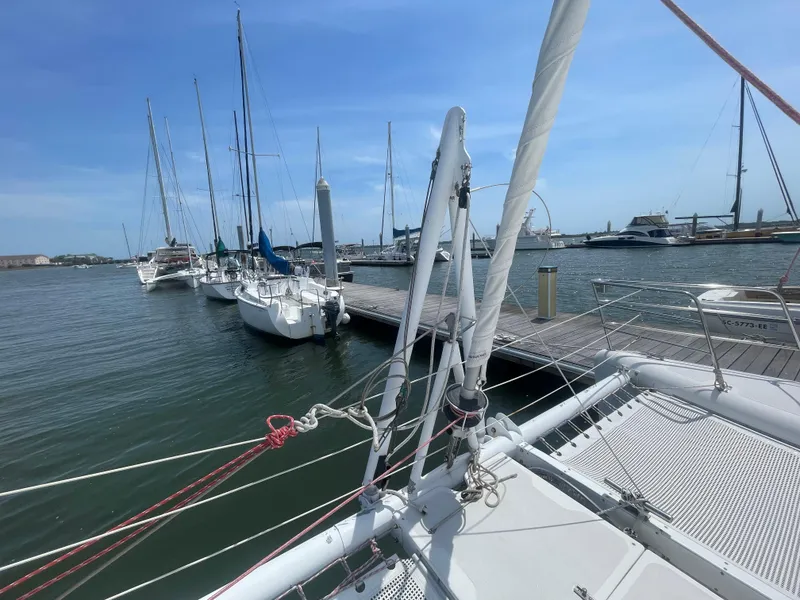Slide: The Image of Seawind 1000 catamaran docked at marina, surrounded by sailboats, under clear blue sky. - 12