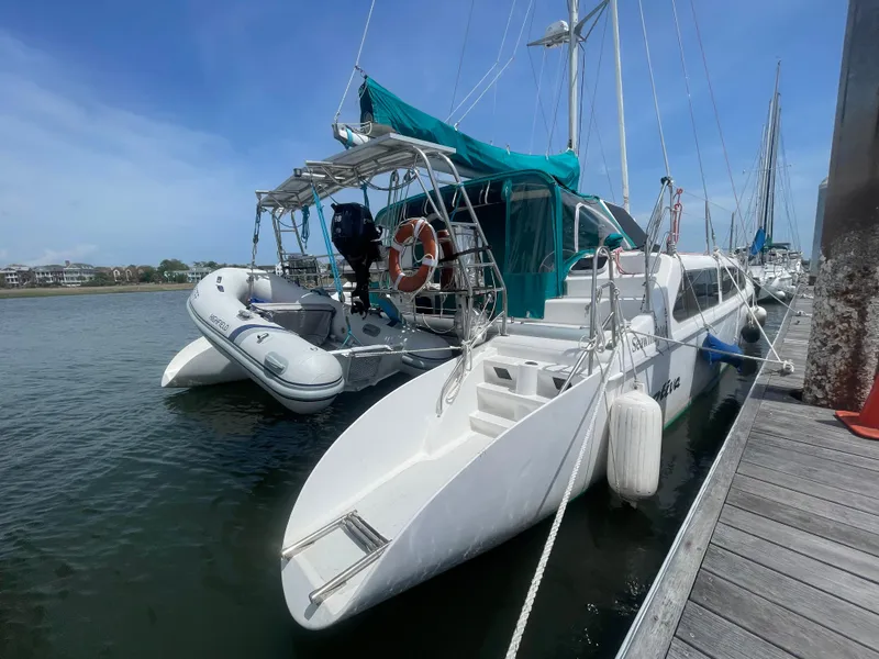 Slide: The Image of Seawind 1000 catamaran from 2001 docked with inflatable dinghy and blue canopy. - 4