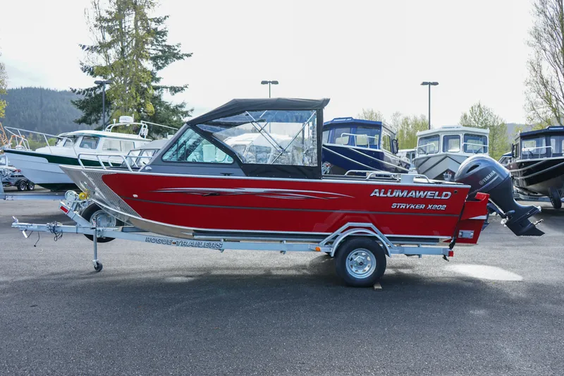 Slide: The Image of 2025 Alumaweld Stryker X202 boat, red exterior, on trailer in a marina setting. - 3
