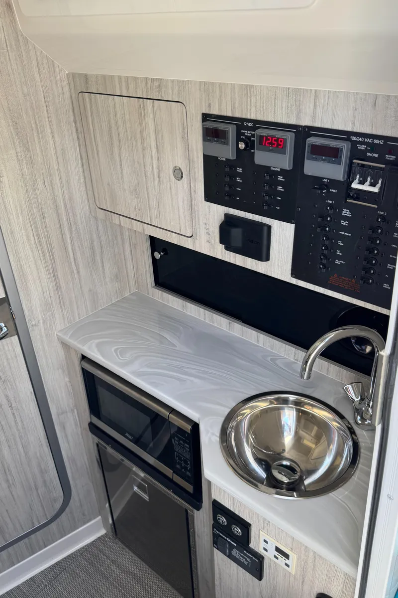 Slide: The Image of 2025 Regulator 37 boat interior with control panel, sink, and compact kitchen area. - 14