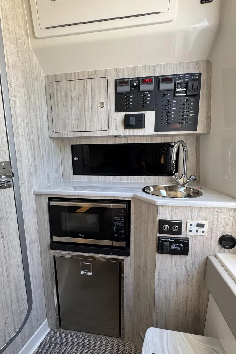 Slide: The Image of Compact kitchen area in a 2025 Regulator 37 boat with microwave, sink, and control panels. - 16