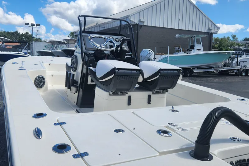 Slide: The Image of 2026 ShearWater X22 HYBRID boat with dual seats and modern dashboard, docked outdoors. - 7
