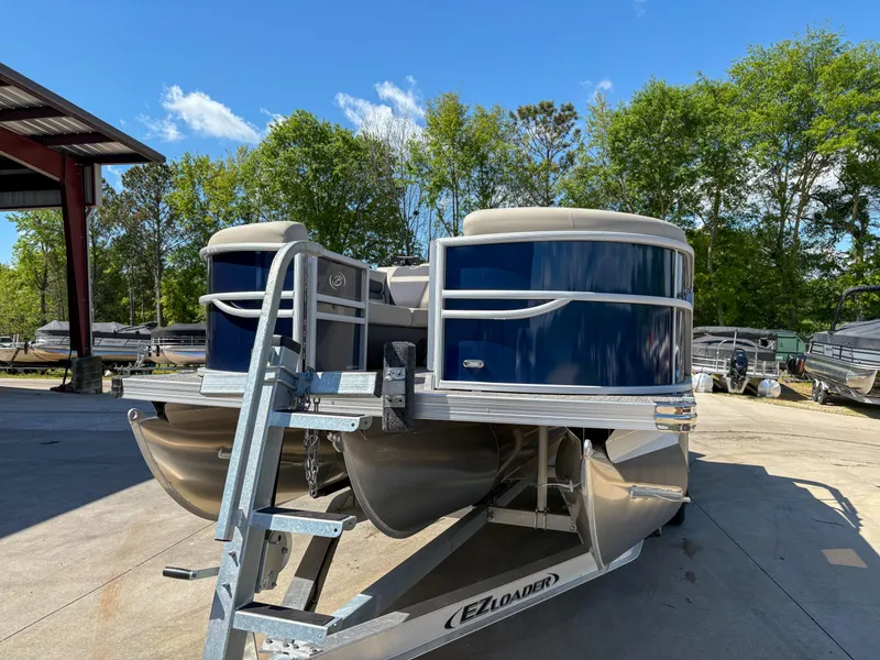 Slide: The Image of 2023 Barletta CABRIO 24 UC pontoon boat on trailer, outdoors with trees in background. - 3