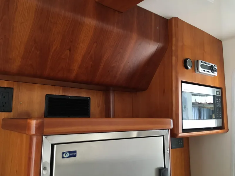 Slide: The Image of Wood-paneled kitchen area in 2008 Calcutta 390 boat with microwave and stainless steel fridge. - 15