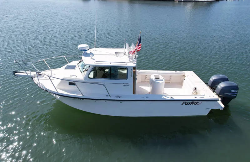 Slide: The Image of 2008 Parker 2520 DV boat on calm water, featuring a cabin and outboard motor. - 2