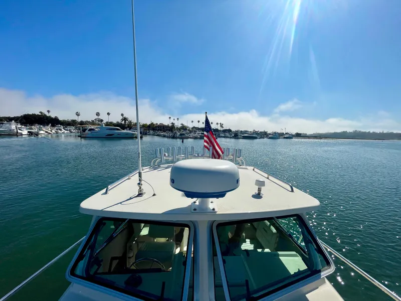 Slide: The Image of 2008 Parker 2520 DV boat on water with American flag, sunny day, marina in background. - 25
