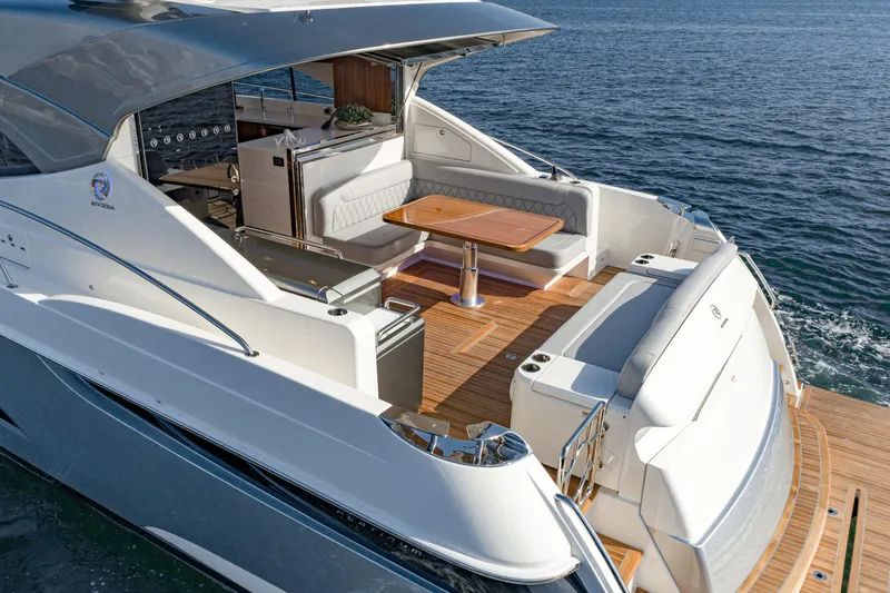 Slide: The Image of 2023 Riviera 5400 Sport Yacht with elegant deck and seating area on the water. - 19
