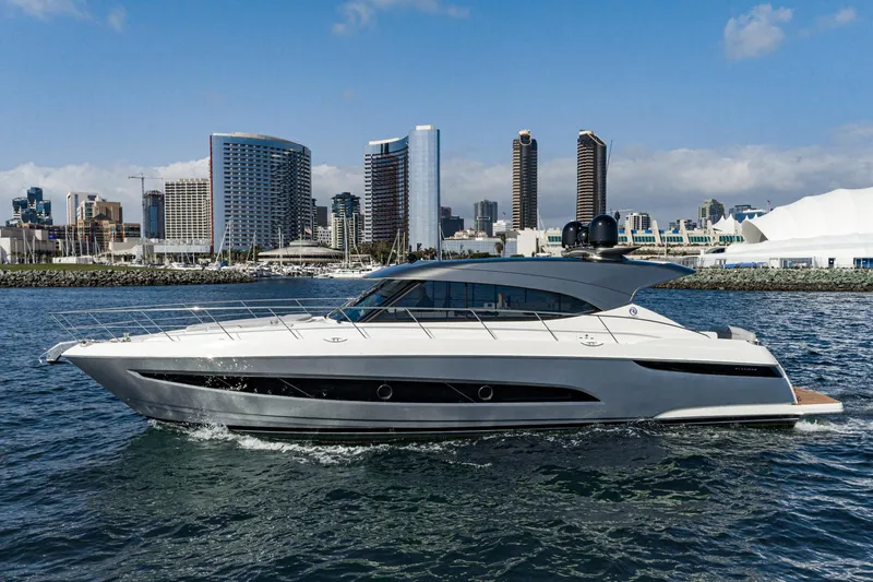 Slide: The Image of 2023 Riviera 5400 Sport Yacht cruising near city skyline on a sunny day. - 2
