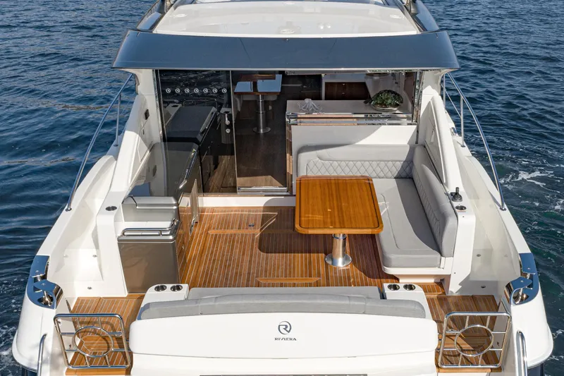 Slide: The Image of 2023 Riviera 5400 Sport Yacht with elegant deck and seating area on the water. - 20