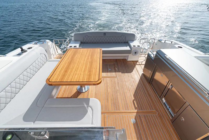 Slide: The Image of Luxurious 2023 Riviera 5400 Sport Yacht deck with elegant seating and wooden table. - 22