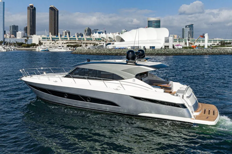 Slide: The Image of 2023 Riviera 5400 Sport Yacht cruising near urban waterfront skyline. - 5