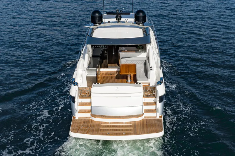 Slide: The Image of 2023 Riviera 5400 Sport Yacht cruising on open water, rear view. - 7