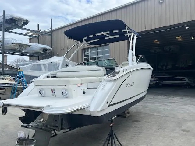 Slide: The Image of 2018 Cobalt R5 boat with canopy, parked outside a warehouse. - 2