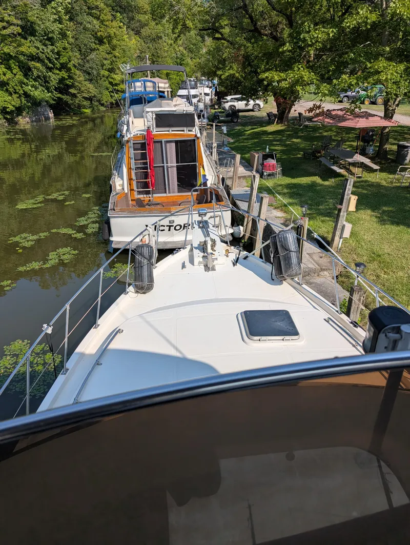 Slide: The Image of 1989 Jefferson 42 SE Sundeck Motor Yacht docked on a serene, tree-lined canal. - 14