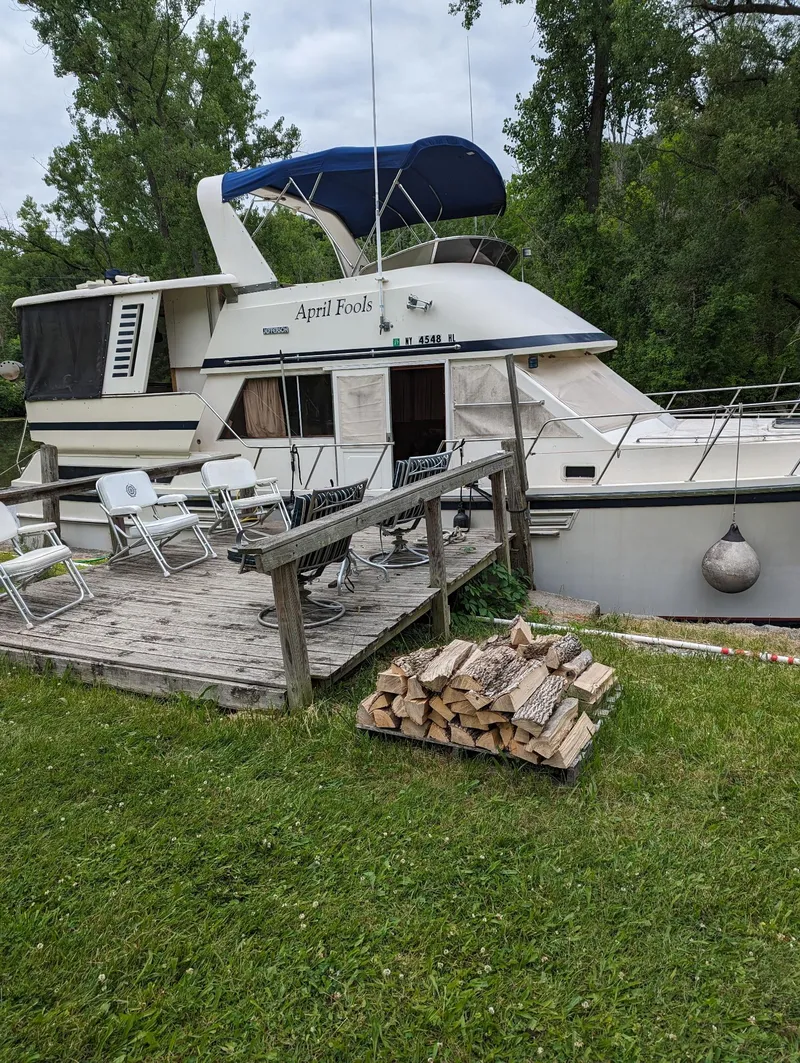 Slide: The Image of 1989 Jefferson 42 SE Sundeck Motor Yacht docked with firewood and chairs nearby. - 2