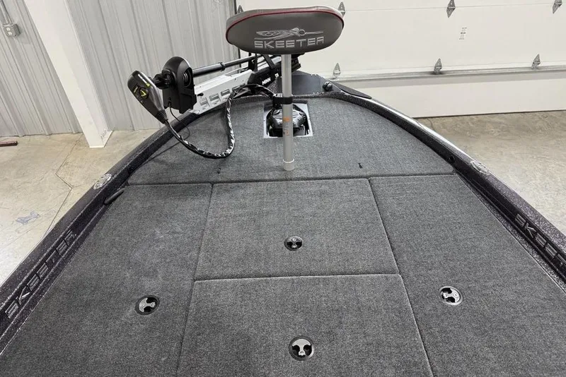 Slide: The Image of 2025 Skeeter ZX150 boat interior with carpeted deck and mounted trolling motor. - 5