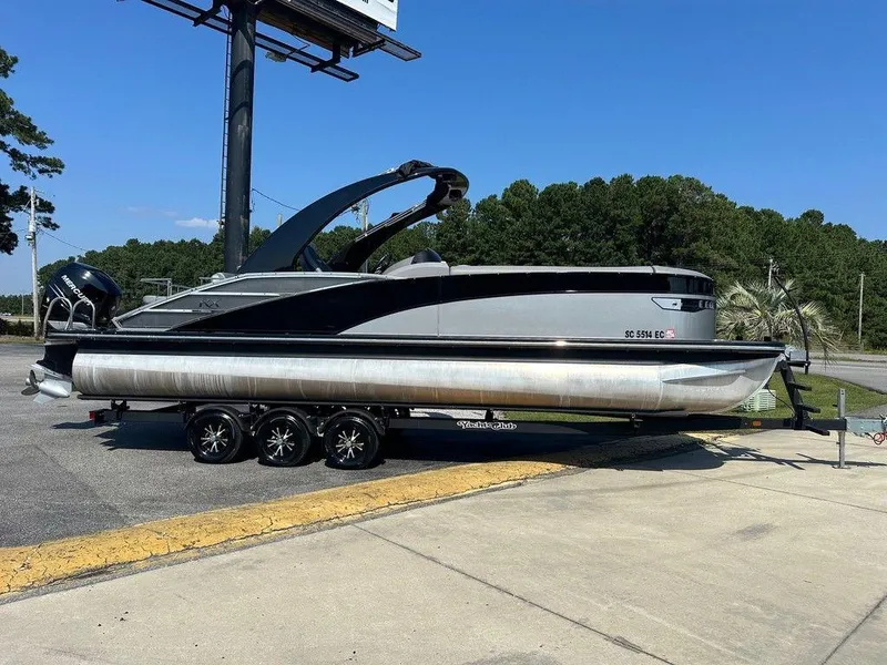 Slide: The Image of 2021 Bennington 25 RXSB pontoon boat on trailer, parked outdoors under clear sky. - 1