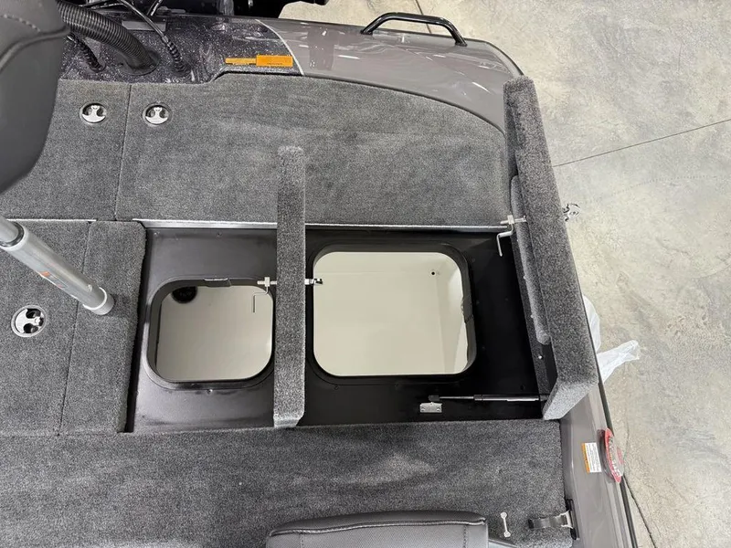 Slide: The Image of 2025 Skeeter ZXR20 boat storage compartment with open hatch, gray carpeted interior. - 21