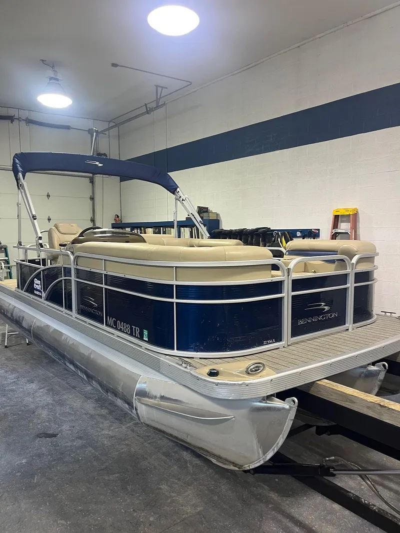 Slide: The Image of 2014 Bennington 22 SSLX pontoon boat in indoor storage, blue and beige color scheme. - 1
