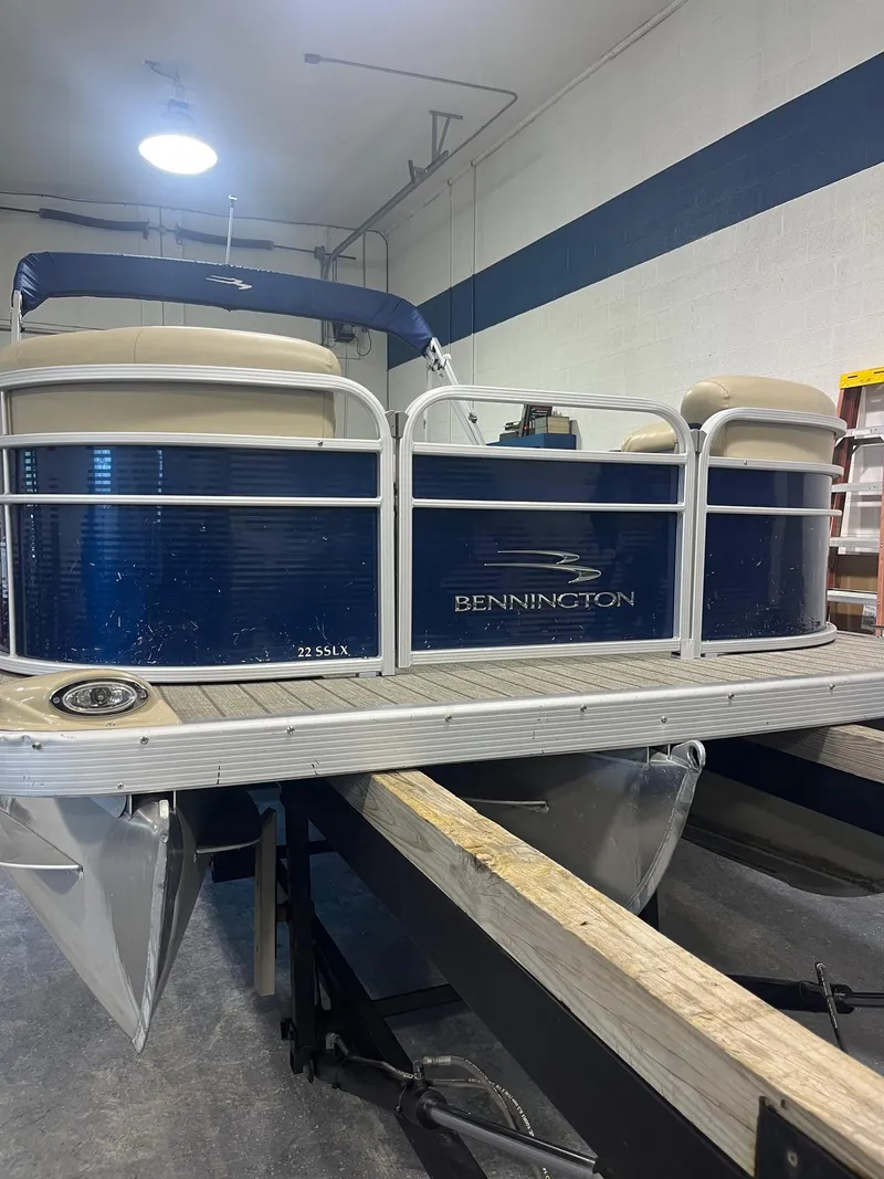Slide: The Image of 2014 Bennington 22 SSLX pontoon boat in indoor storage, blue and white design. - 10