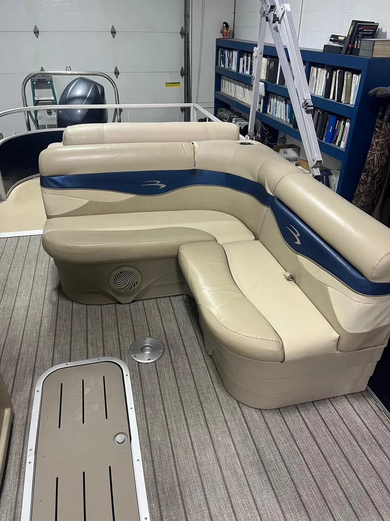 Slide: The Image of 2014 Bennington 22 SSLX pontoon boat interior with beige seating and blue accents. - 2