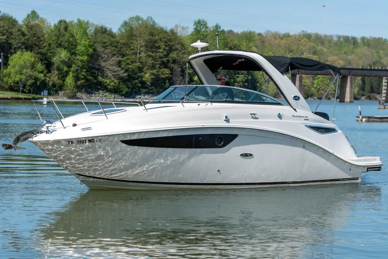 Slide: The Image of 2014 Sea Ray 260 Sundancer boat on calm water, surrounded by lush greenery. - 0