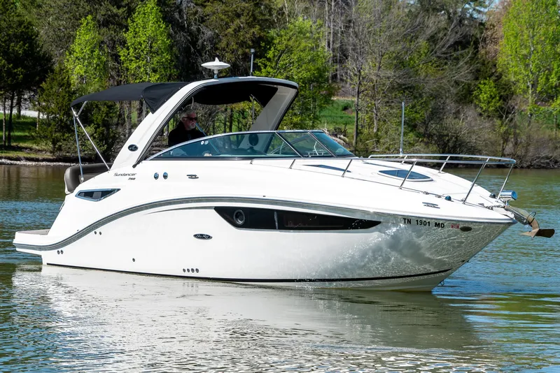 Slide: The Image of 2014 Sea Ray 260 Sundancer cruising on a serene lake with lush green trees. - 1