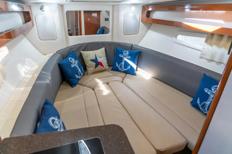 Slide: The Image of 2014 Sea Ray 260 Sundancer cabin with beige seating, nautical-themed pillows, and wood accents. - 24