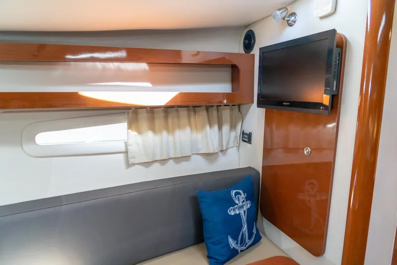 Slide: The Image of Interior of 2014 Sea Ray 260 Sundancer with TV, seating, and anchor-themed pillow. - 25