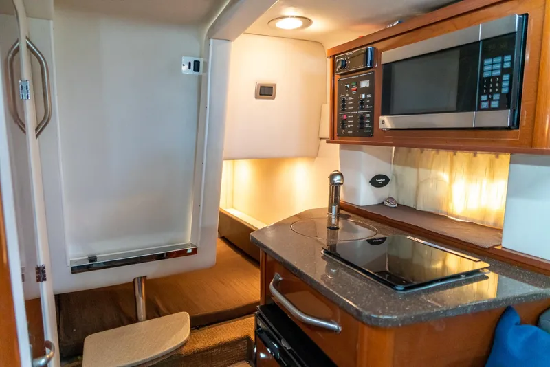 Slide: The Image of Interior of 2014 Sea Ray 260 Sundancer with kitchenette, microwave, and seating area. - 28
