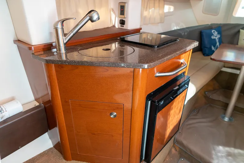 Slide: The Image of 2014 Sea Ray 260 Sundancer cabin with kitchenette, featuring sink, stove, and compact fridge. - 31