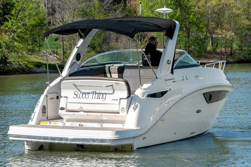 Slide: The Image of 2014 Sea Ray 260 Sundancer boat cruising on a calm lake with lush greenery. - 5