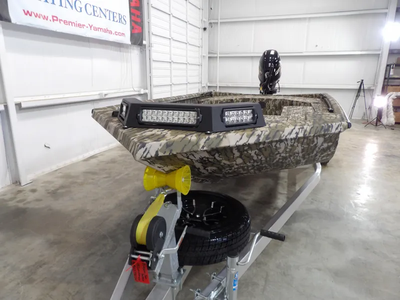 Slide: The Image of 2025 Avid 18 Commander boat with camouflage design on a trailer in a showroom. - 10