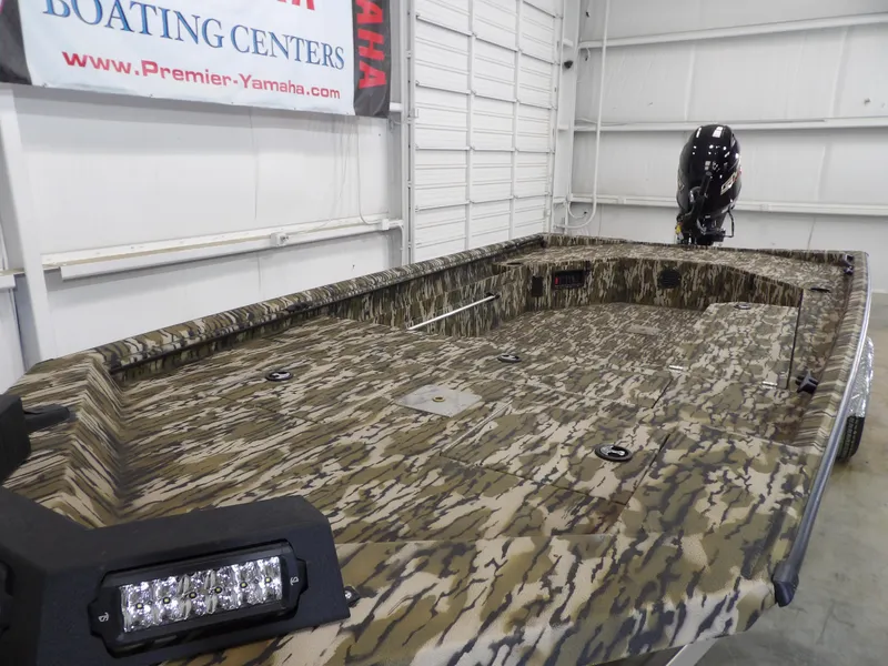 Slide: The Image of 2025 Avid 18 Commander boat with camouflage design in a showroom. - 11