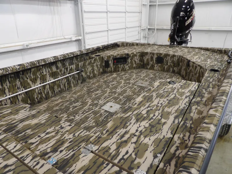Slide: The Image of 2025 Avid 18 Commander boat with camouflage design in a garage setting. - 13