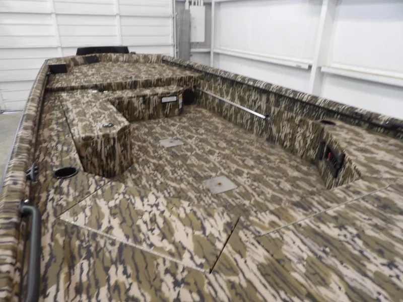 Slide: The Image of 2025 Avid 18 Commander boat with camouflage interior in a garage setting. - 15