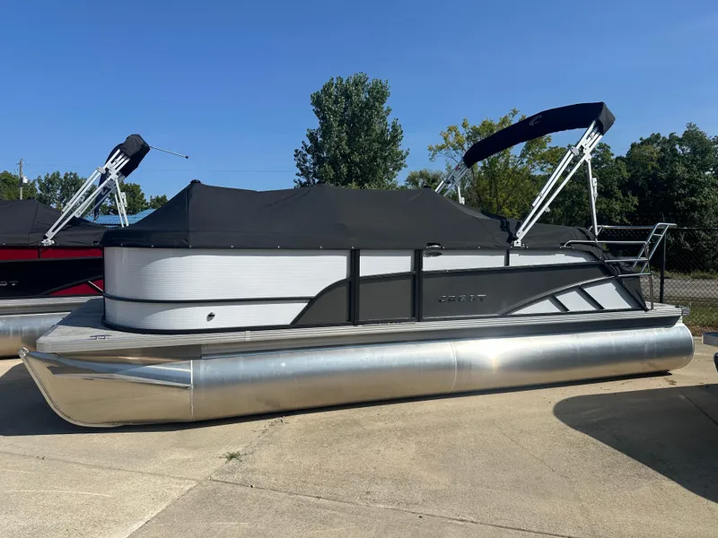 The Image of 2024 Crest Classic LX 220 SLSC pontoon boat with black canopy, parked outdoors. - 1