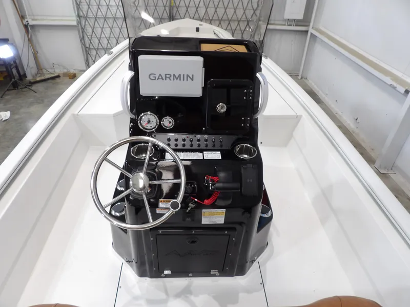 Slide: The Image of 2025 Avid 21FST boat console with Garmin navigation, steering wheel, and gauges in a warehouse setting. - 18