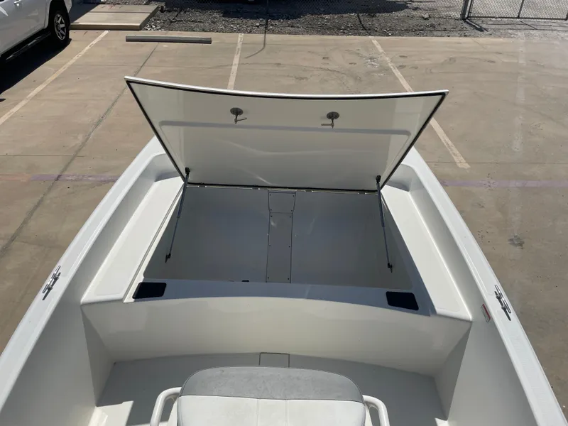 Slide: The Image of 2020 Mako Pro Skiff 17 boat with open storage compartment in a parking lot. - 17