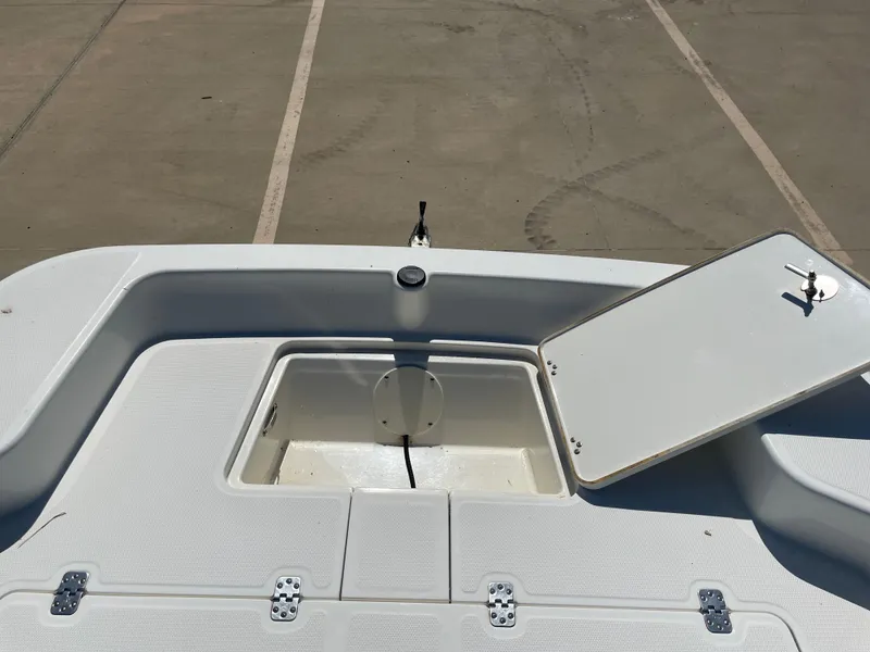 Slide: The Image of 2020 Mako Pro Skiff 17 boat storage compartment with open hatch in a parking lot. - 18