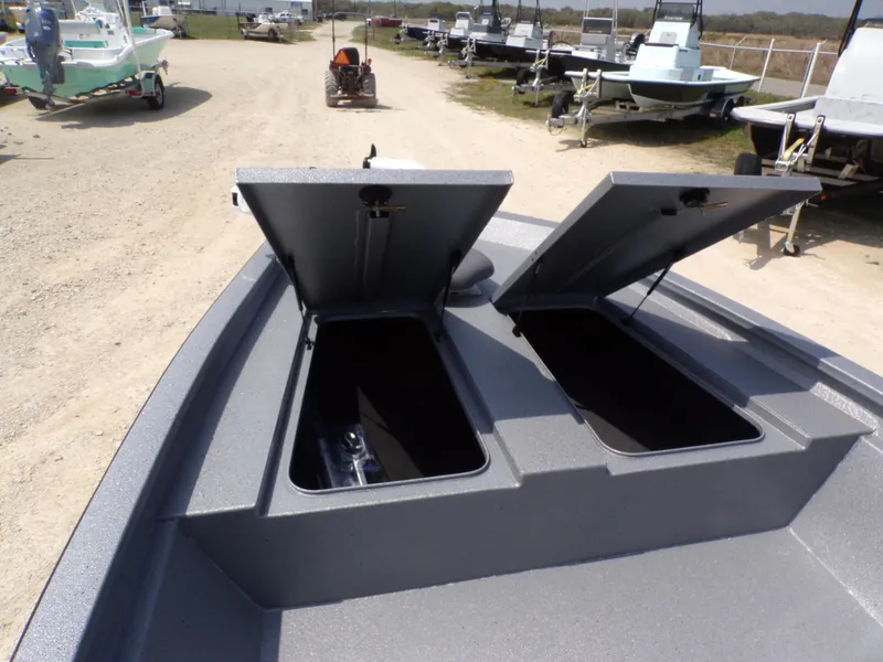Slide: The Image of 2025 Xpress H210BAY boat with open storage compartments, parked on a gravel lot. - 16
