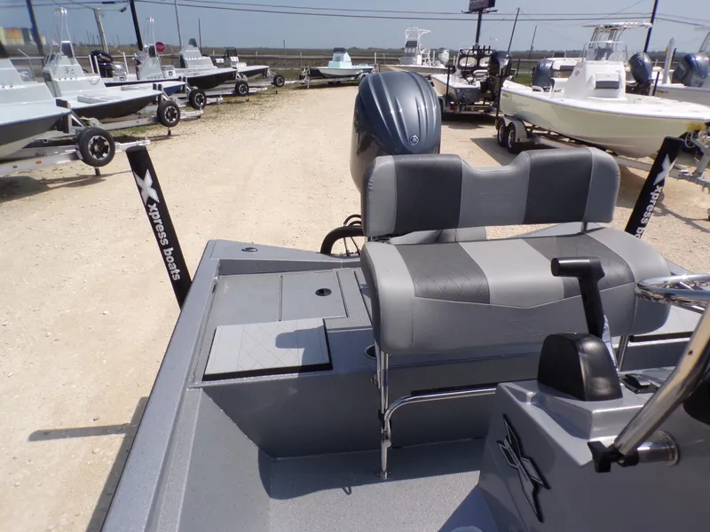 Slide: The Image of 2025 Xpress H210BAY boat interior with seating and motor, displayed outdoors. - 21